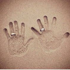 two hand prints in the sand, one has a ring on it