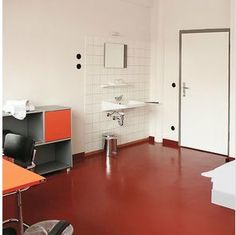 an empty room with red floors and white walls