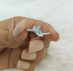 a woman's hand holding an engagement ring with a diamond on the top and bottom