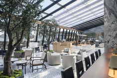 a restaurant with tables, chairs and trees in the middle of it is lit up by lamps