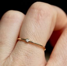 a woman's hand with a diamond ring on her left finger and the other hand holding it