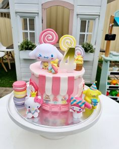 a pink and white cake with candy decorations on it's top sitting on a table