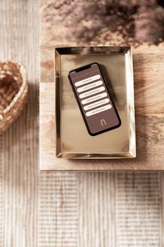 a cell phone sitting on top of a wooden table next to a heart shaped basket