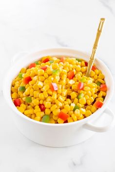 a white bowl filled with corn and candy on top of a marble counter next to a gold spoon