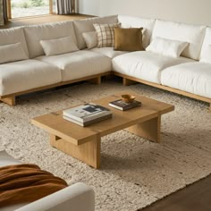 a living room filled with white couches and wooden coffee table in front of a window