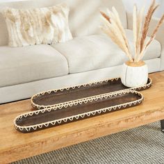 two decorative trays sitting on a coffee table in front of a couch with pillows