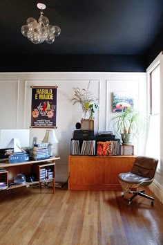 a living room with hard wood floors and white walls, an old record player on the sideboard