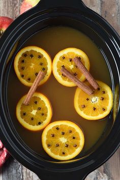 sliced oranges and cinnamon sticks in a pot of water