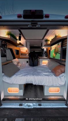 the interior of a camper van with two beds and televisions in the back