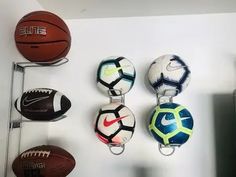 there are many different sports balls hanging on the wall in this room, and one has a keychain