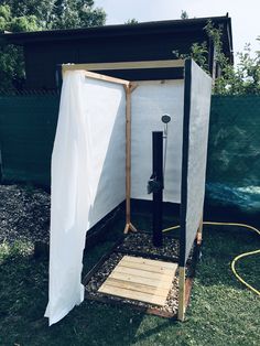 an outdoor shower in the middle of a yard with a white sheet on it's side