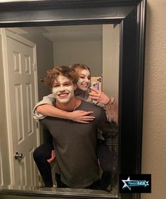 a man and woman are taking a selfie in front of a mirror with their faces painted