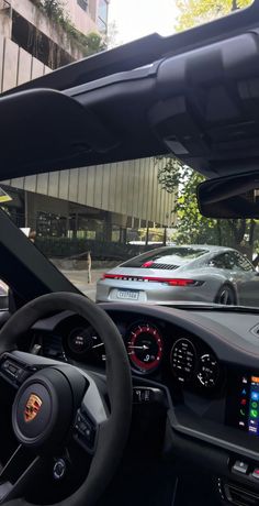 the interior of a car with dashboard lights and steering wheel controls in front of a building