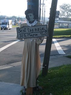 a statue is holding a sign that says best tag sale on the side of a street