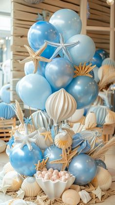 a blue and white cake with starfish balloons on top, seashells and shells