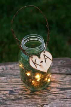 a mason jar with some string lights in it and a wooden heart on the lid