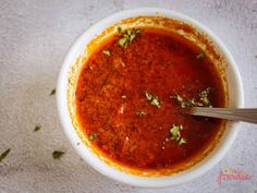 a white bowl filled with sauce and garnished with parsley