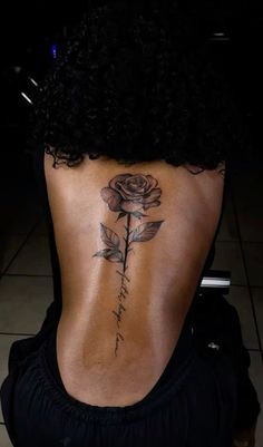 a woman's back with a rose tattoo on it