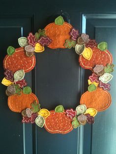 a wreath made out of felt with autumn leaves and pumpkins on the front door