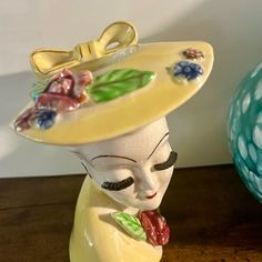 a ceramic figurine with a hat on it's head sitting next to a vase