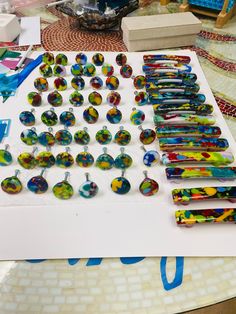 several pairs of earrings are displayed on a table with other items in the foreground