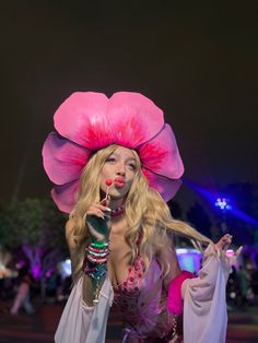 a woman in a pink hat and dress holding a microphone