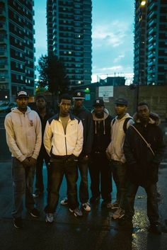 a group of young men standing next to each other on a city street at night