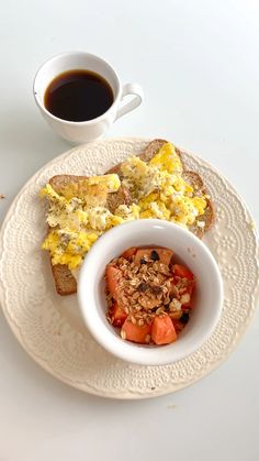 a white plate topped with toast and vegetables next to a cup of coffee