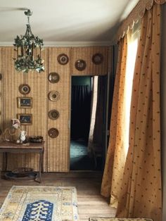 a living room filled with furniture next to a window covered in drapes and curtains