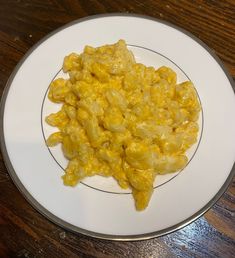 a white plate topped with macaroni and cheese on top of a wooden table