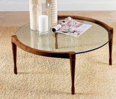 a glass coffee table with wooden legs and a magazine on the top, in a living room