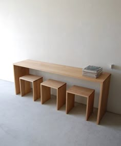 a wooden bench with three stools next to it and a book on the table