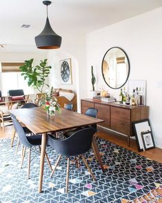 a dining room table with blue chairs and a large mirror on the wall above it