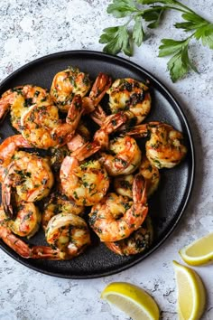 grilled shrimp on a plate with lemon wedges and parsley garnish