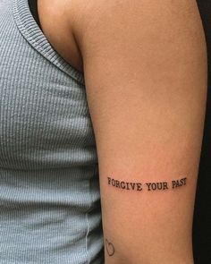 a woman with a tattoo on her arm that says, for give your past