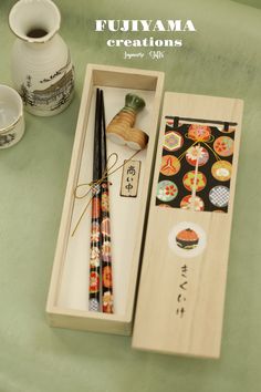 an open box with two chopsticks and some other items in it on a table