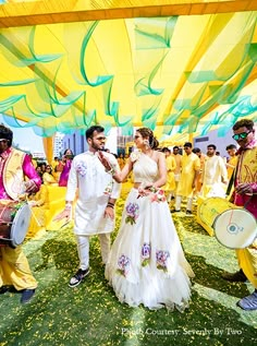 a bride and groom walking down the aisle at their wedding ceremony with colorful decorations in the background