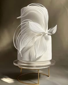 a three tiered cake with white icing on a metal stand and gold base