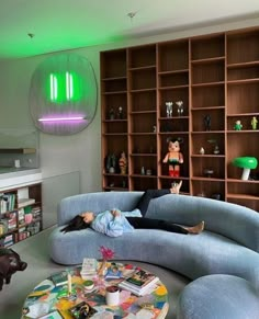 a person laying on a couch in a living room with bookshelves and shelves