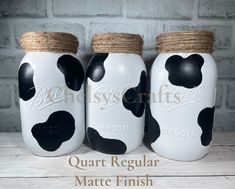 three painted mason jars with black and white cows on them