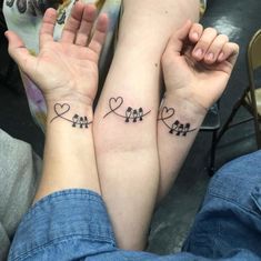 two people holding hands with tattoos on their arms and the other hand has hearts in them