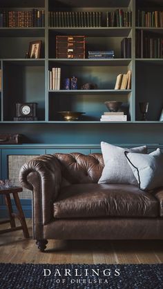 a brown leather couch sitting in front of a bookshelf