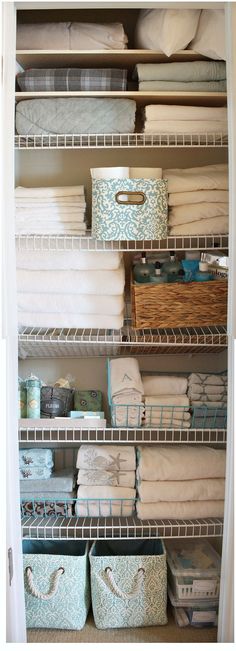 an organized closet with baskets and folded towels