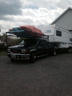 a truck is parked in front of a trailer with surfboards on it