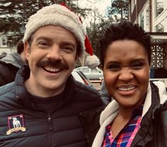 a man in a santa hat standing next to a woman wearing a jacket and scarf