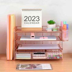 a desk with a calendar, pen holder and other office supplies on top of it