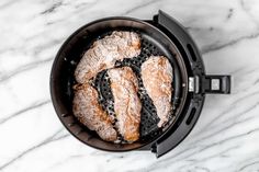 some type of bread in a pot on a marble counter top with black grates