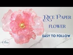 a pink flower sitting on top of a white table next to a marble slab with the words rice paper flower easy to follow