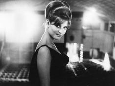 black and white photograph of a woman in a dark dress holding a piano keyboard, looking at the camera