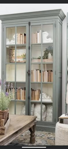 a bookcase with many books in it next to a wooden table and chair on the floor